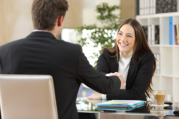 Image of a woman and a man shaking hands and smiling