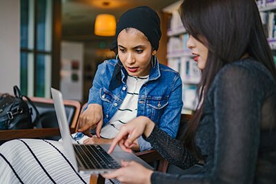 two women using a laptop