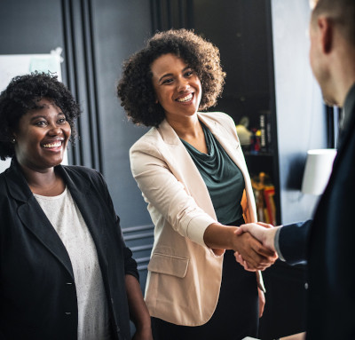 two people shaking hands as a third person looks on