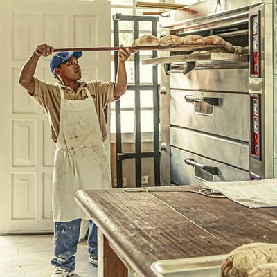 Baker pulling bread out of oven