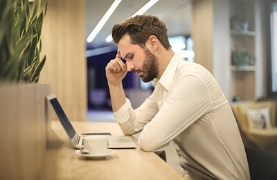 Man sitting at desk in front of laptop thinking