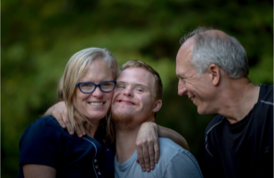 family outdoors, son embracing his parents