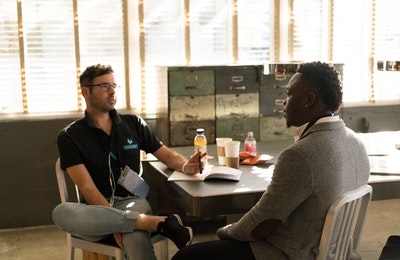 Two persons sitting at a desk speaking to each other