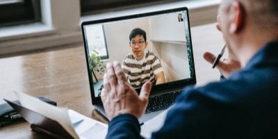 Two people and a participant are in a video call on a laptop.