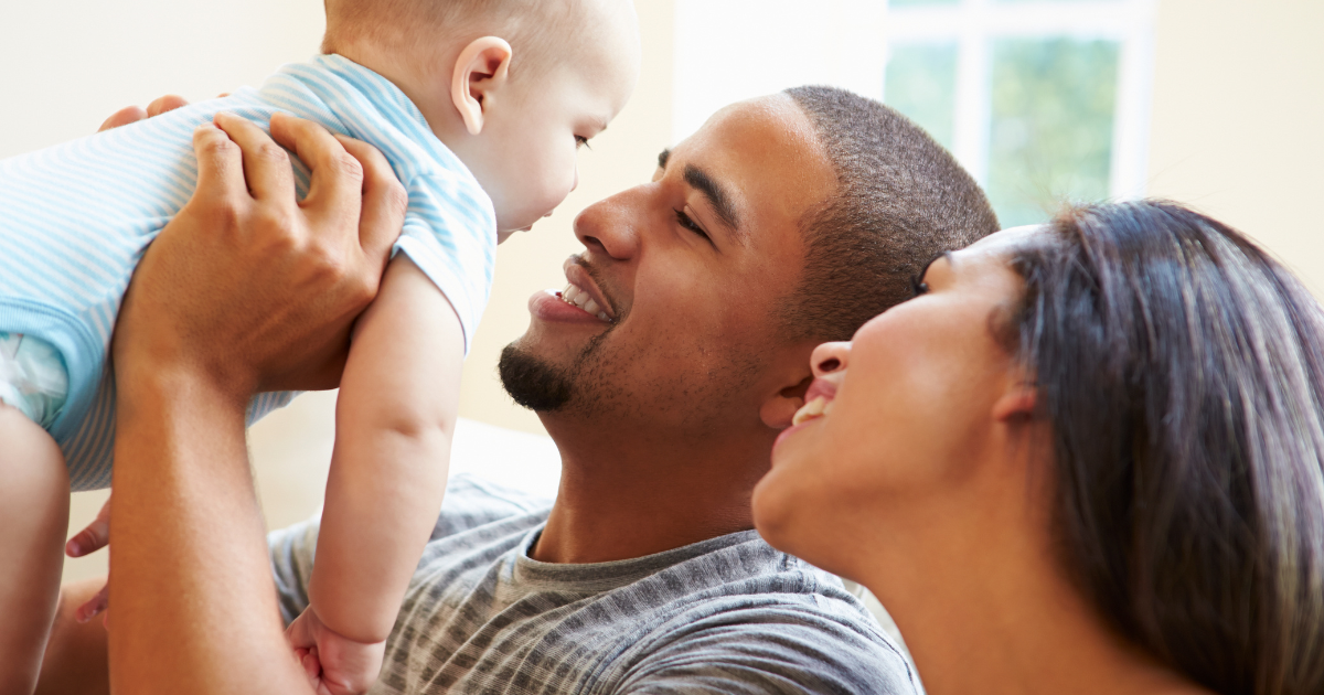 Two parents holding and looking up at their baby.