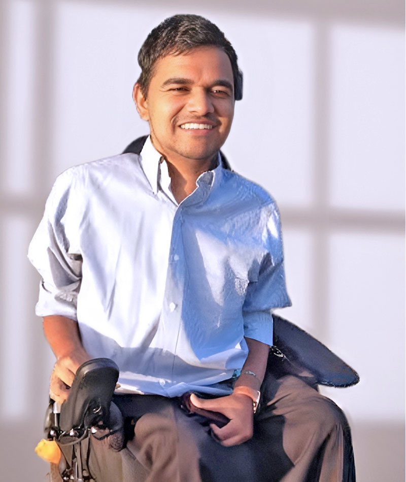 Kushal sitting in wheelchair wearing a blue shirt