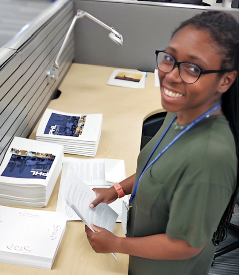 Adrienne standing behind a desk, smiling.