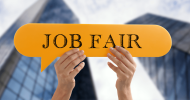 Hands holding up a yellow bubble sign that says, “Job Fair”. 