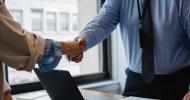 two people shaking hands across a desk